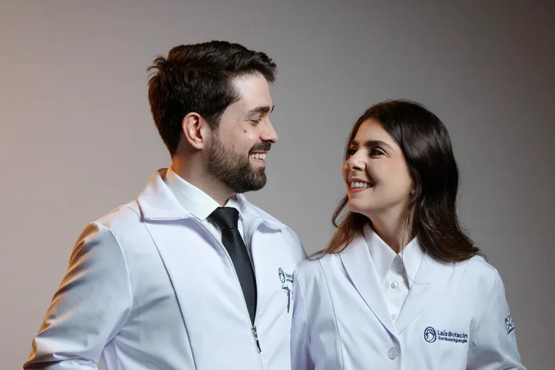 Dr. Mateus Capuzzo e Dra. Laís Botacin de jaleco, conversando