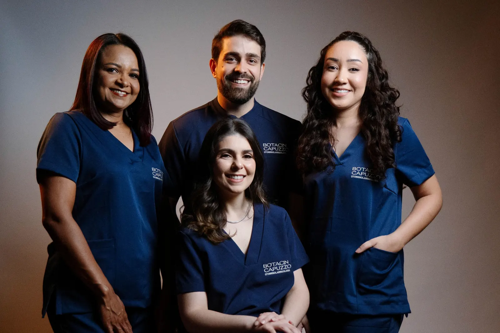 Equipe da Botacin Capuzzo: Dra. Laís Botacin, Dr. Mateus Capuzzo e a equipe de recepção, de uniforme azul